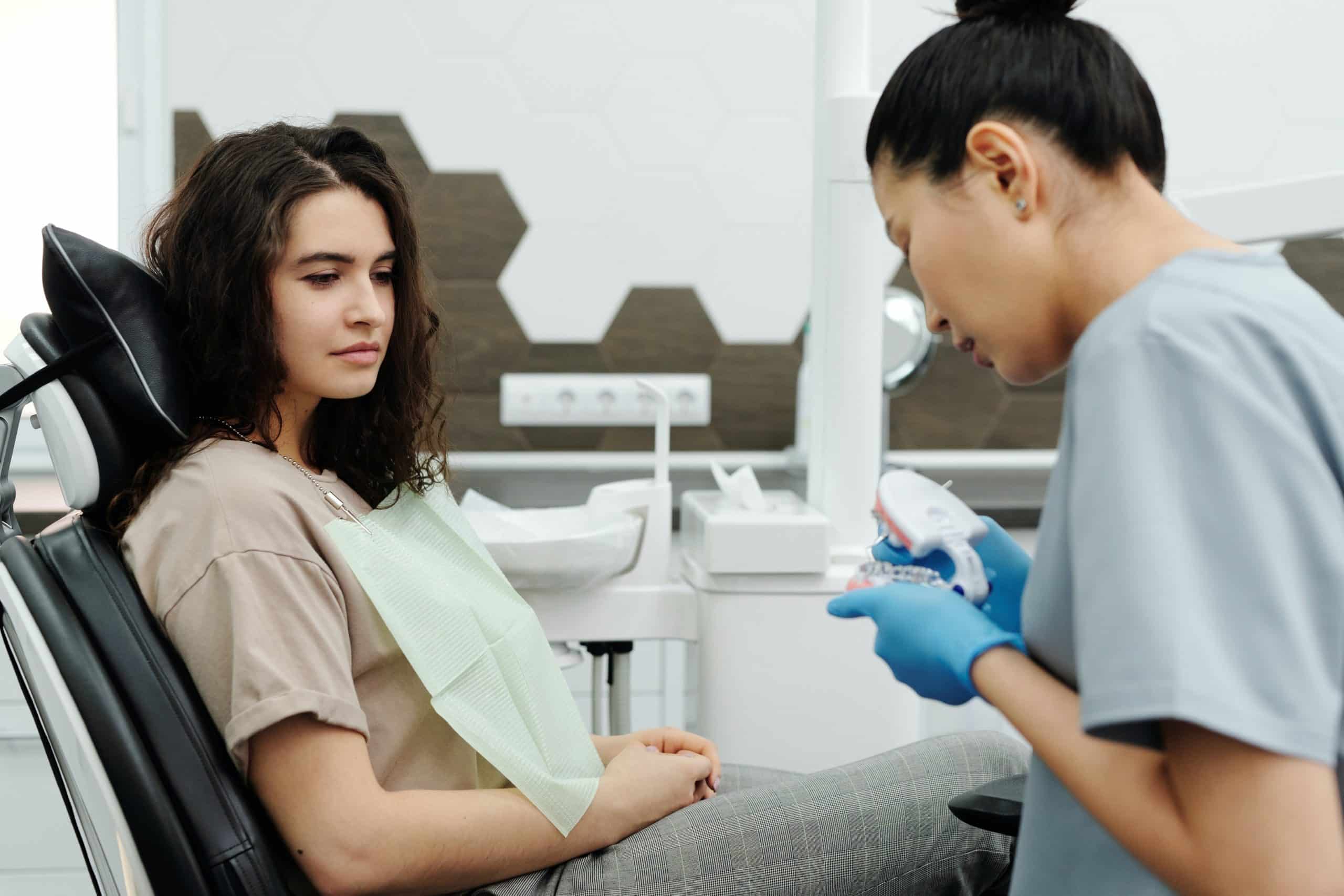 Top New Year’s Resolutions To Benefit Your Smile dentist showing a tooth model to a patient
