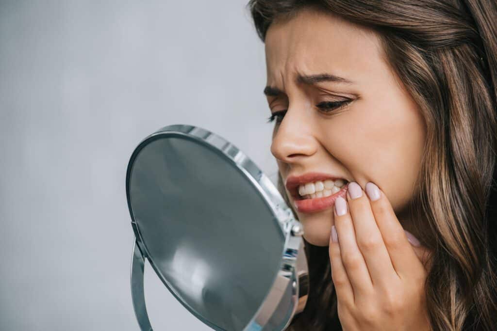 Close-up view of young woman having toothache and looking at mirror
Are Teeth Naturally White or Yellow?