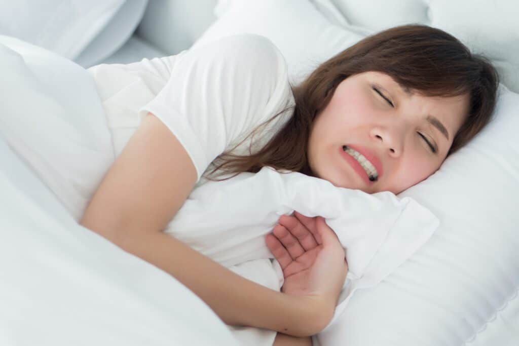 stressed woman with grinding teeth, bruxism symptoms; portrait of stressful, exhausted, tired sleeping woman grinding her teeth with stress; oral, dental care medical concept; asian adult woman model. How Does Mouth Breathing Affect Teeth?